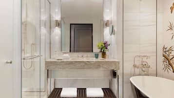 A modern bathroom with a glass-enclosed shower, a marble vanity, and a freestanding bathtub.