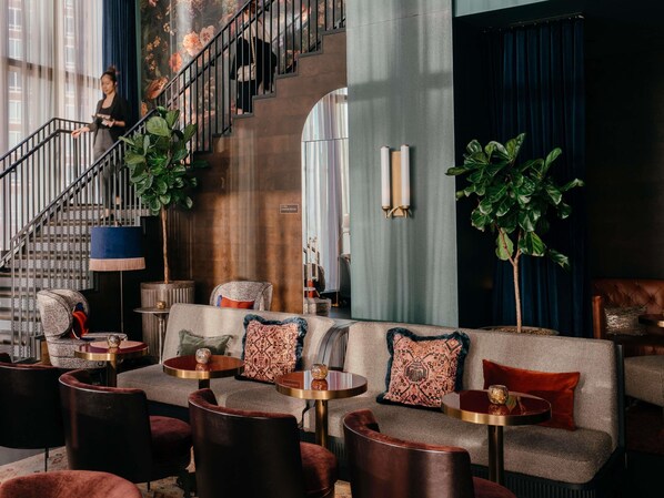 A lobby with a staircase, seating area, and a powder room.