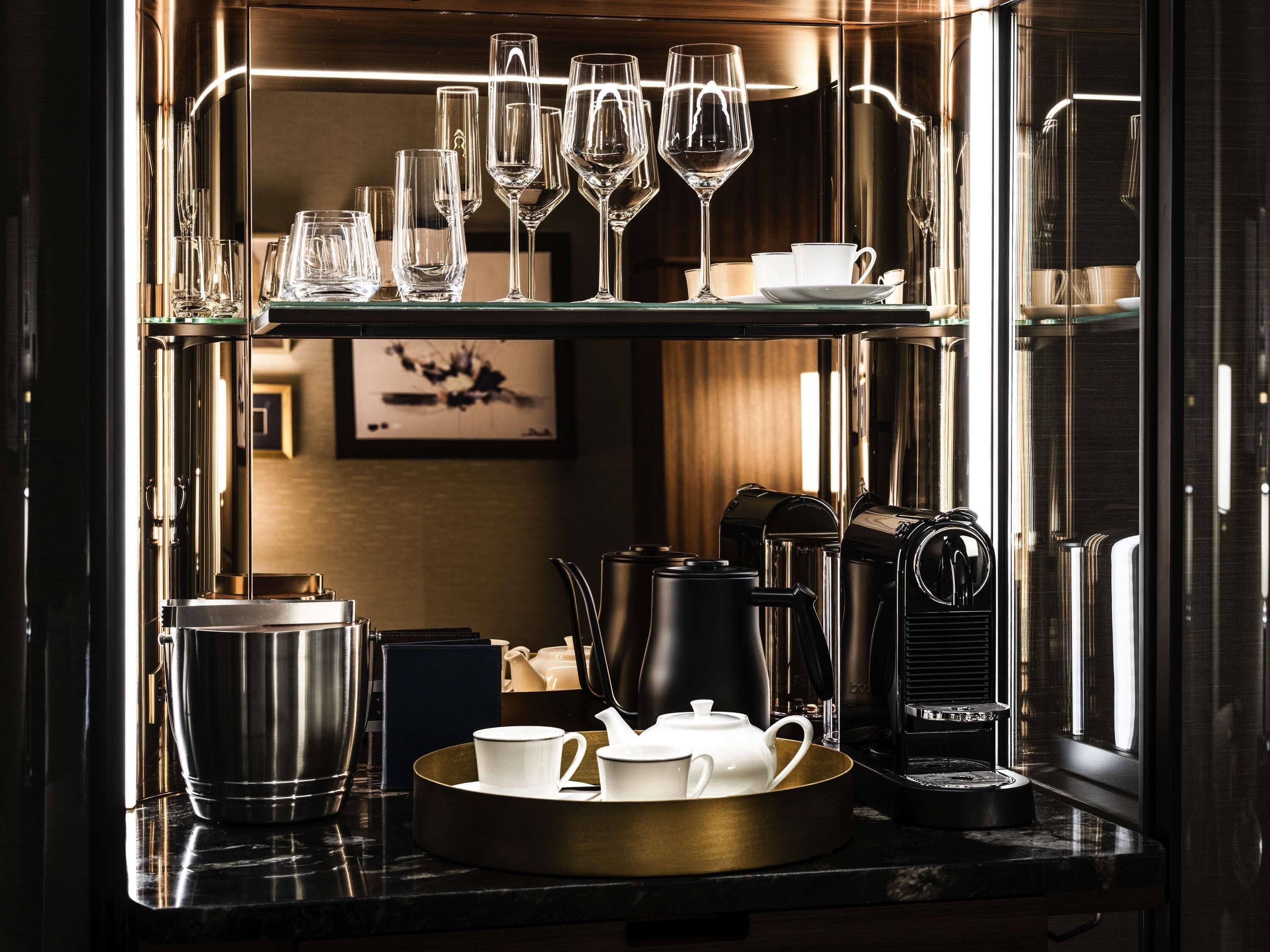 Eine Bar mit verschiedenen Gläsern, Tassen und einer Kaffeemaschine.