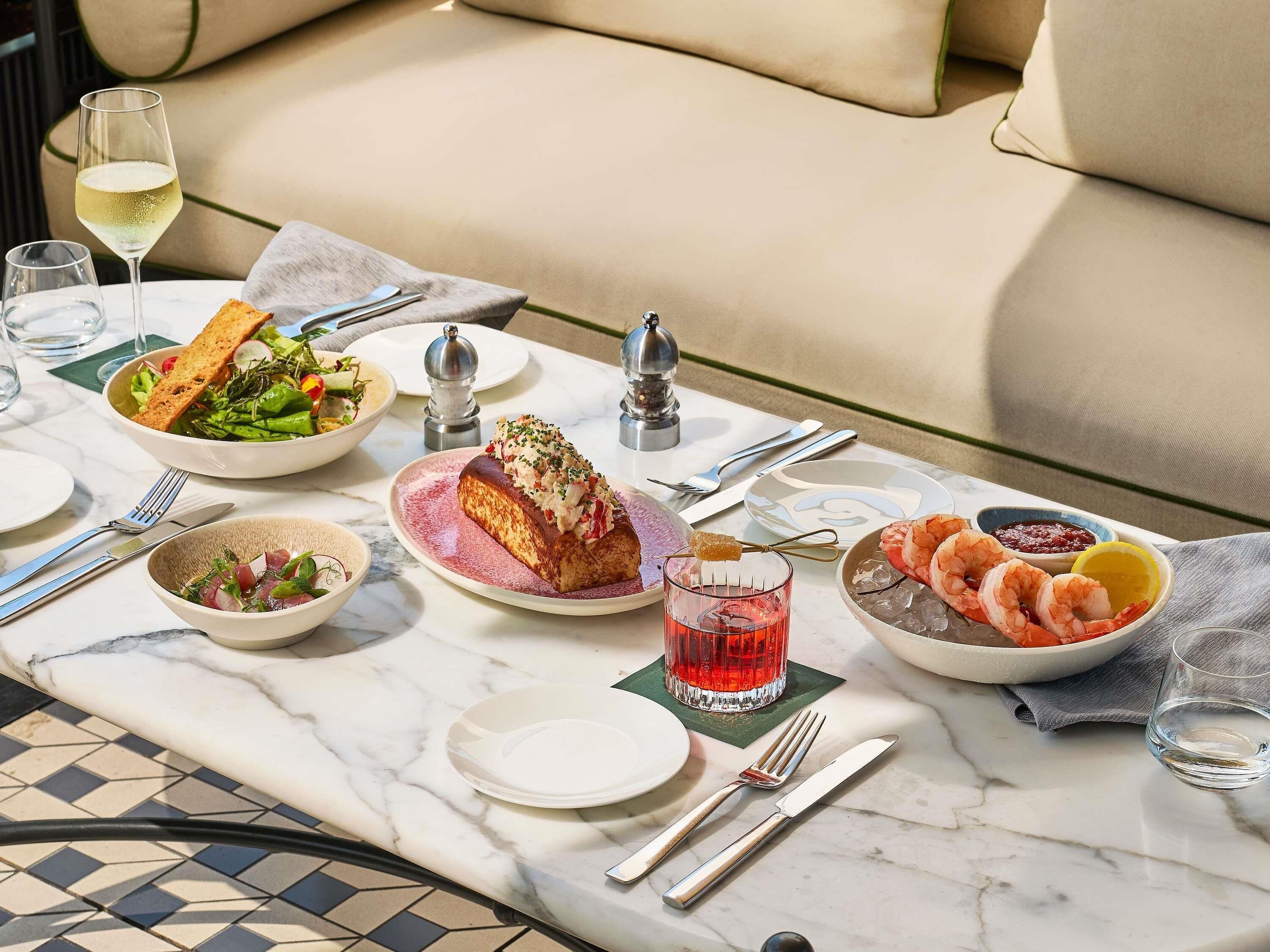 A dining table with various dishes, utensils, and a glass of red drink.
