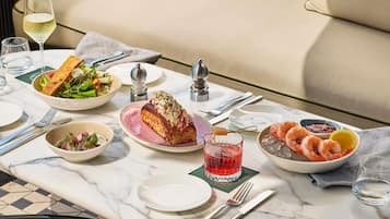 A dining table with various dishes, utensils, and a glass of red drink.