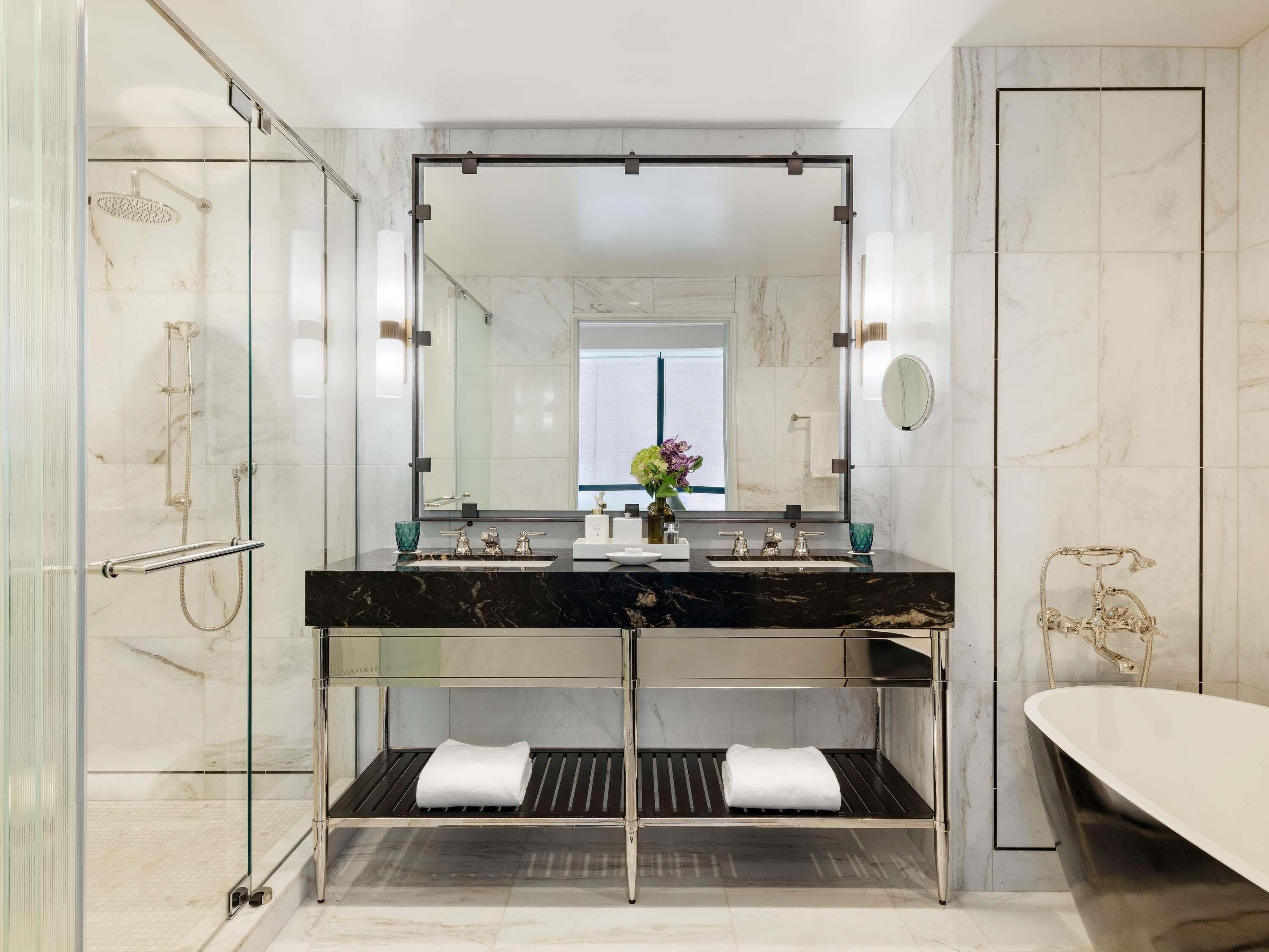 A modern bathroom with a glass-enclosed shower, a double sink vanity, and a freestanding bathtub.