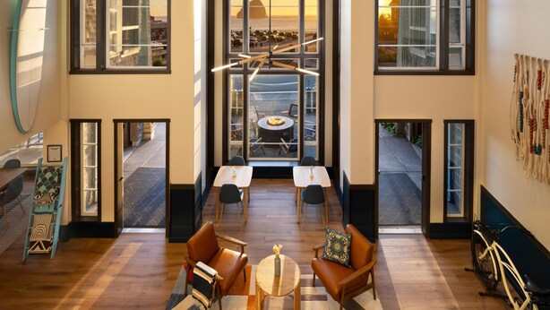 A spacious room with large windows, a dining area with a table and chairs, and a bicycle in the corner. - Inn at Cape Kiwanda (Pacific City)
