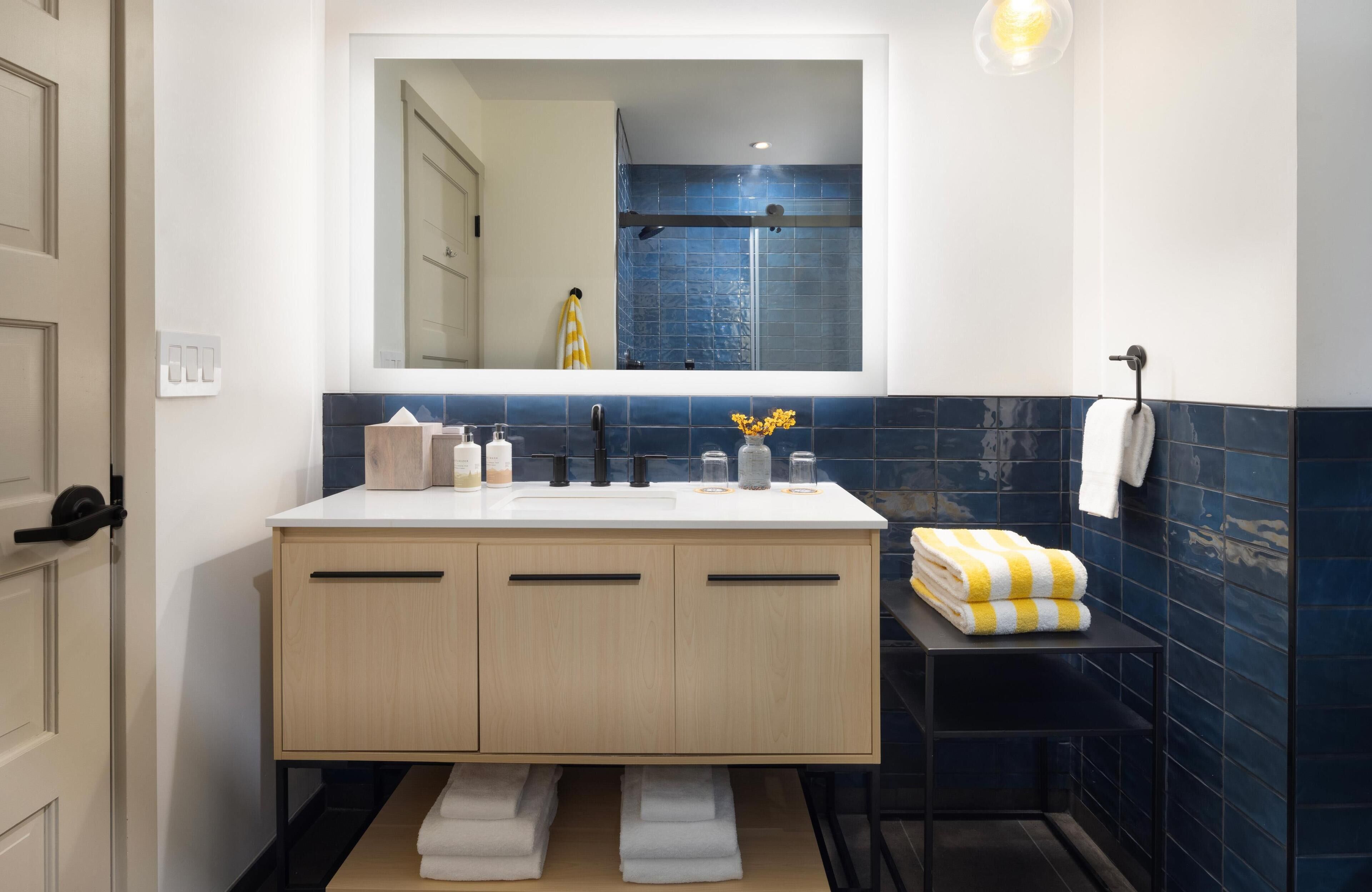 Un baño moderno con tocador doble, un espejo grande y zona de ducha.