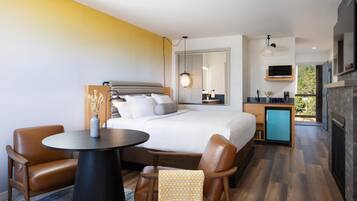 Una moderna camera d'albergo con un letto grande, una scrivania, un'area salotto e un camino.