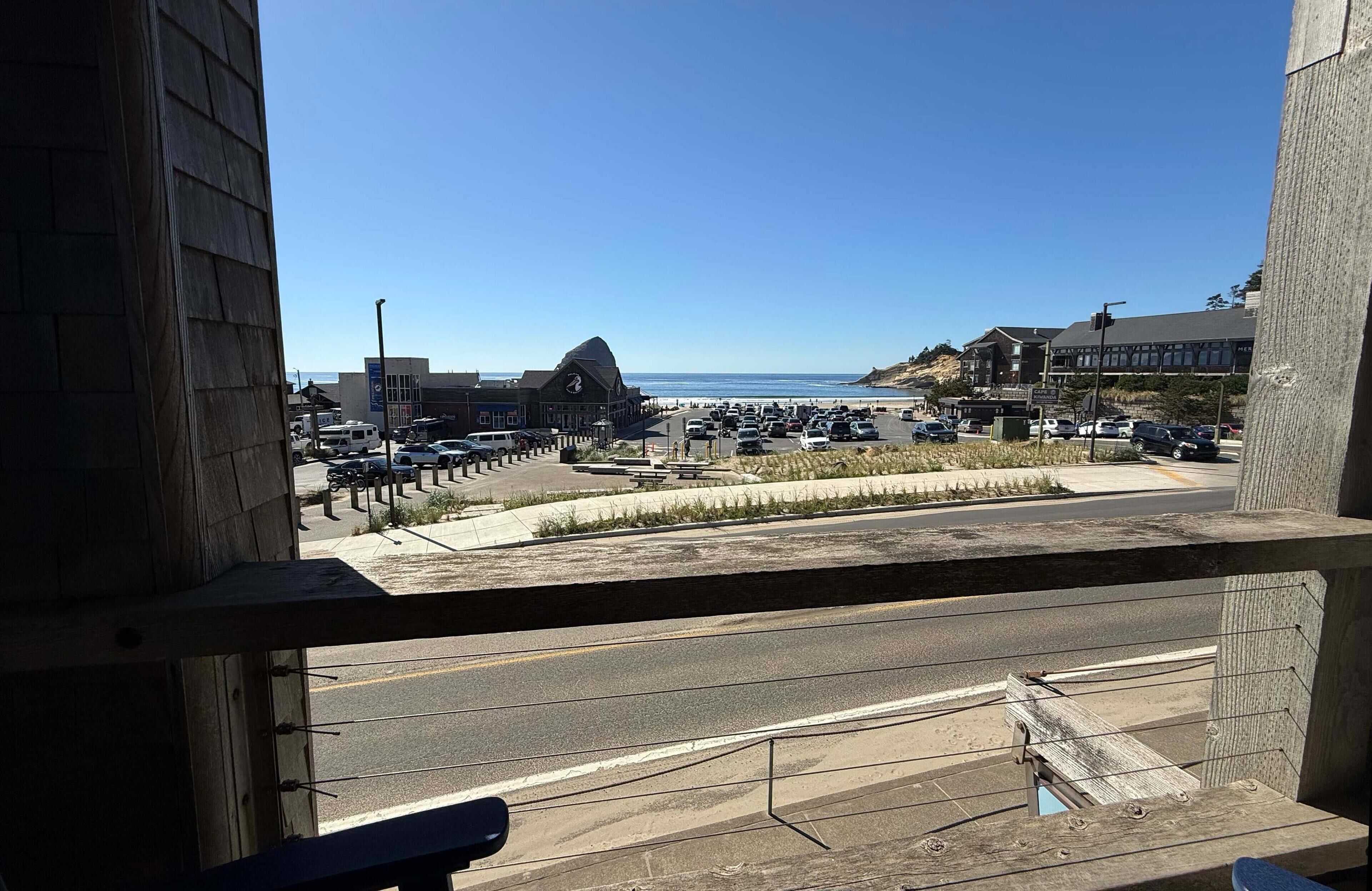 A view from a balcony overlooking a parking lot and a beach.