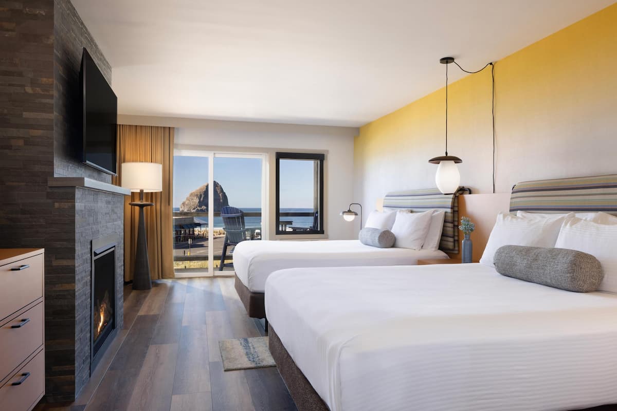 A hotel room with two beds, a fireplace, a TV, and a balcony with a view.