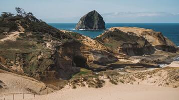 Un paisaje costero con terreno rocoso, una destacada formación rocosa y una playa.