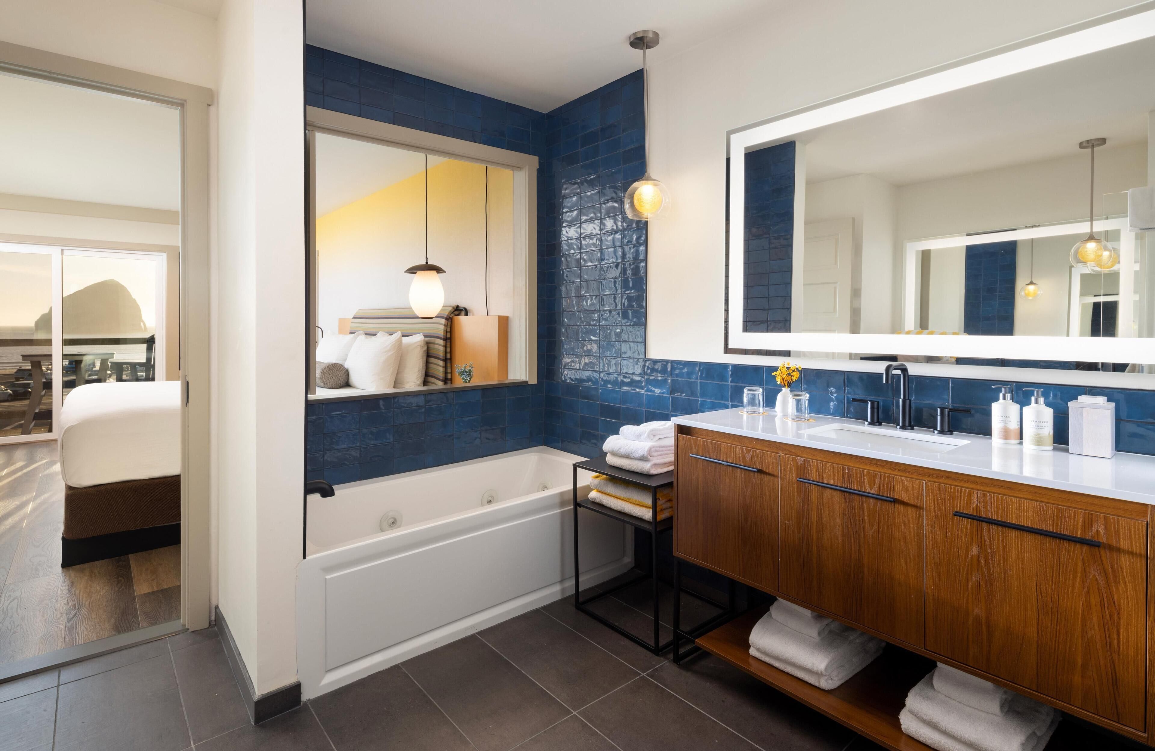 Un baño moderno con una bañera, un tocador de madera con un espejo grande y una pared de acento azul.