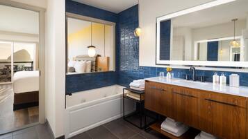 Un baño moderno con una bañera, un tocador de madera con un espejo grande y una pared de acento azul.