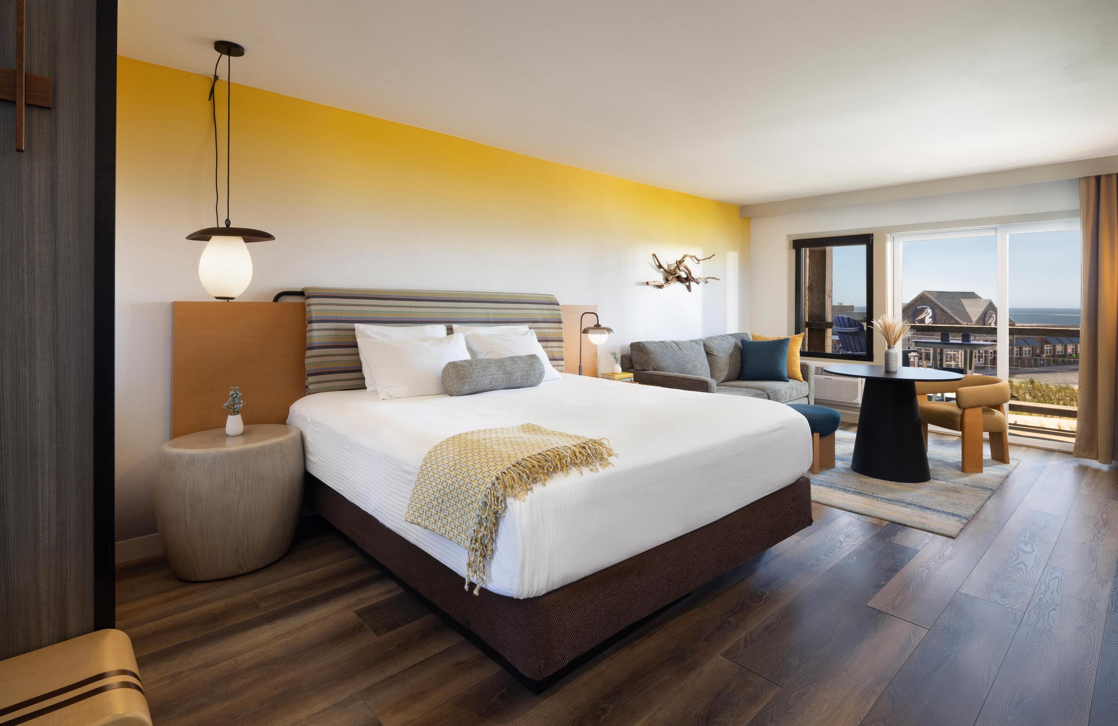 A modern hotel room with a large bed, a seating area with a view, and a balcony.