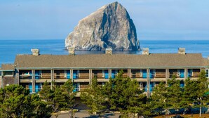 A motel with a large rock formation in the background. - Inn at Cape Kiwanda (Pacific City)