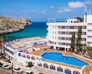 A hotel with a pool, a view of the sea, and a sign reading 'SIMAR'.