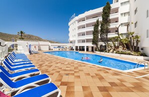 Una piscina al aire libre, sombrillas, tumbonas