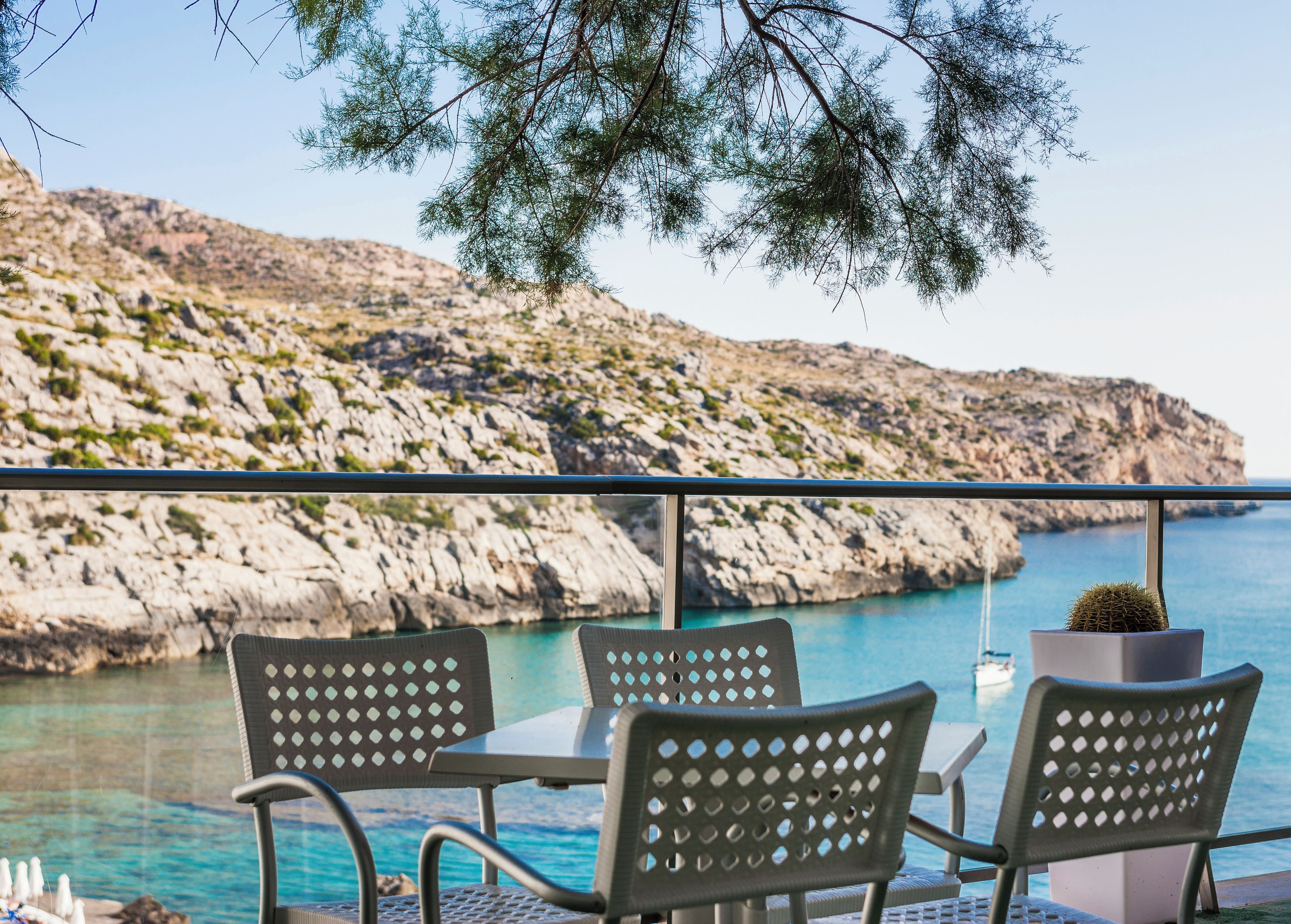 Una terraza con asientos al aire libre y vistas al mar y colinas rocosas.