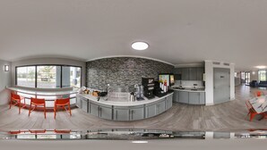 Une cuisine moderne dotée d’un îlot central aux lignes courbes, d’un pare-feu en pierre et d’un espace dédié à la préparation du café.