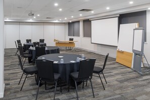 A conference room with a round table, black chairs, a whiteboard, and a projector. - Oaks Perth Hotel (Perth)