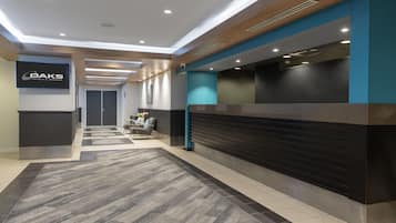 A hotel reception area with a modern design, including a reception desk, seating area, and a sign for OAKS Hotels & Resorts.