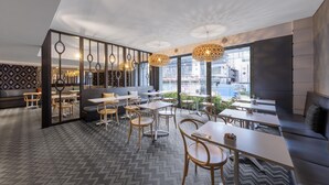 A modern restaurant with a herringbone floor pattern, wooden furniture, and large windows offering a view of the city. - Oaks Perth Hotel (Perth)