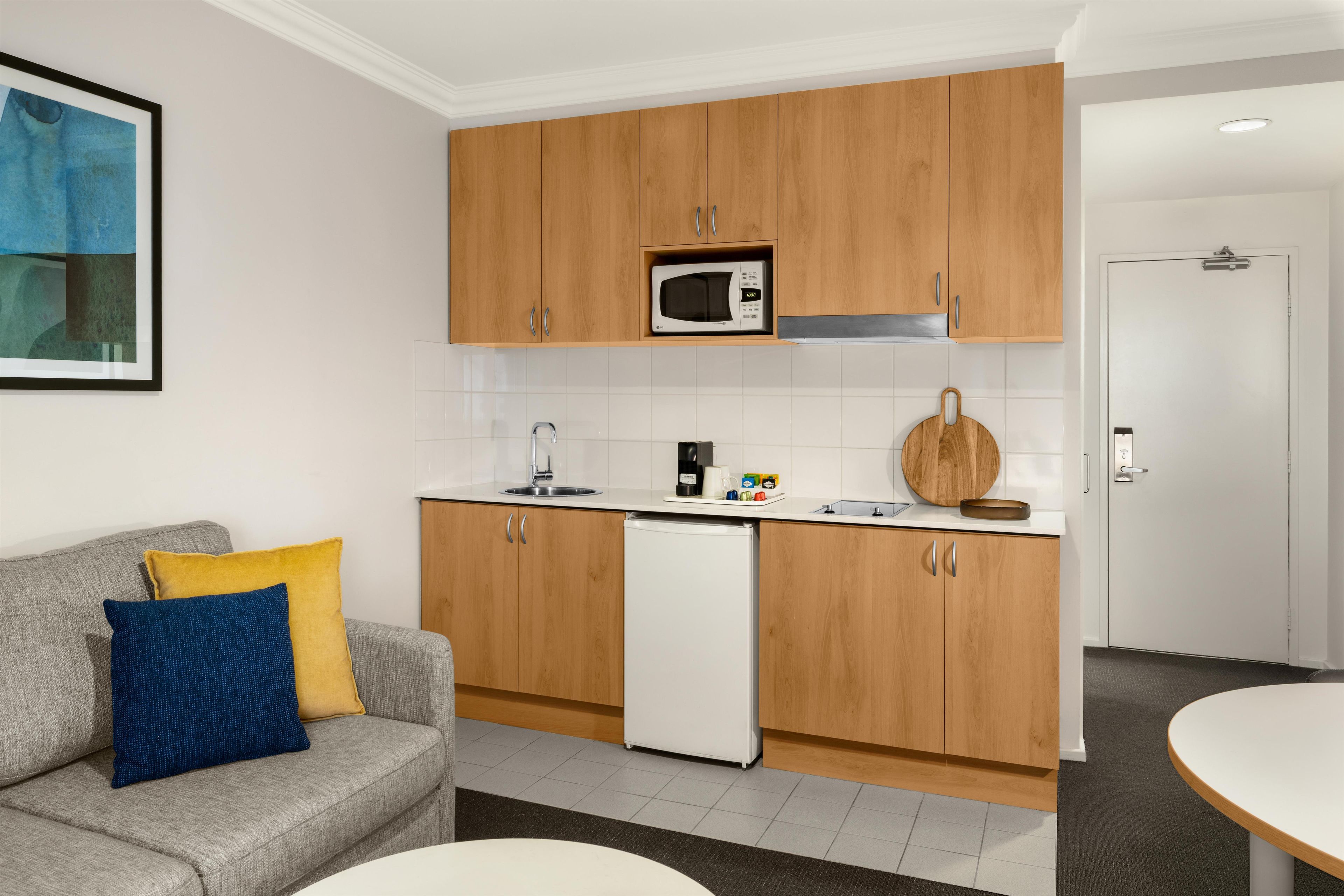 Una cucina compatta con mobili in legno, un frigorifero bianco e un forno a microonde.