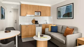 A compact living space with a kitchenette, a dining area, and a seating area with a sofa and a coffee table.