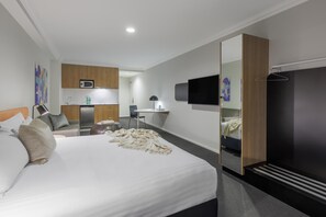 A modern hotel room with a large bed, a desk, a flat-screen TV, and a wardrobe. - Oaks Perth Hotel (Perth)