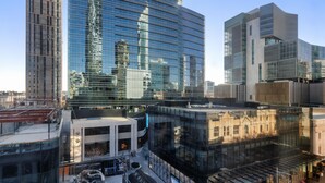 A modern building with a glass facade, a courtyard with seating, and a Louis Vuitton store. - Oaks Perth Hotel (Perth)