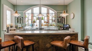 Zona de bar con una isla grande, taburetes y una estantería para vinos al fondo.
