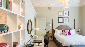 Une chambre d’hôtel avec un lit, un bureau et une chaise, une bibliothèque et une porte.