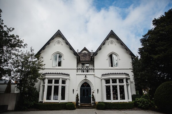 A white building with a symmetrical facade, two prominent towers, and a central entrance with a decorative arch. - Didsbury House Hotel (Manchester)