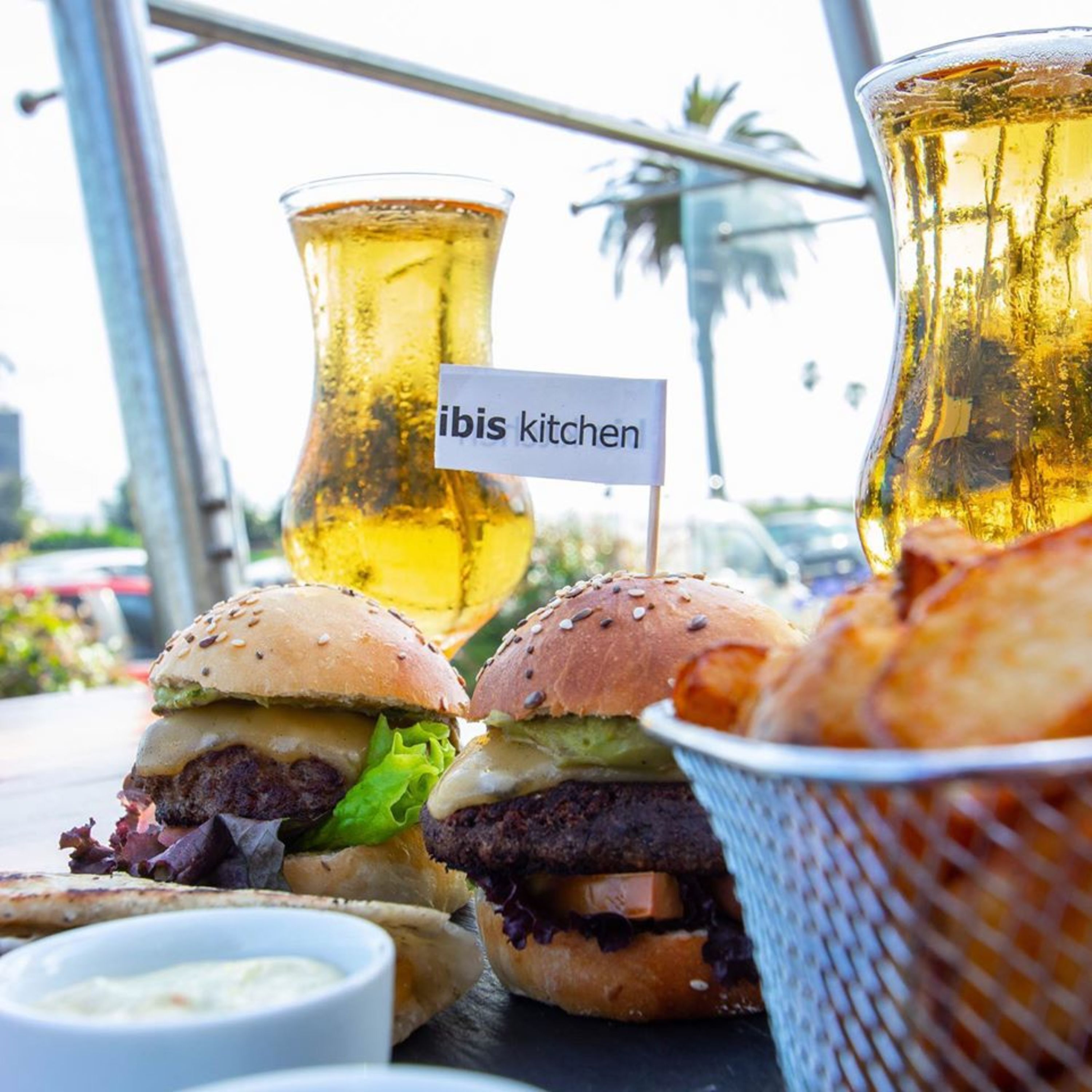 A meal with burgers, fries, and a drink, with a sign reading "ibis kitchen".