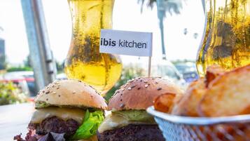 A meal with burgers, fries, and a drink, with a sign reading "ibis kitchen".