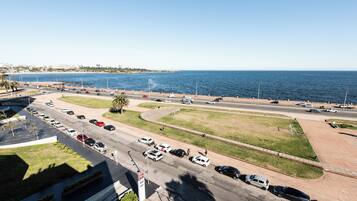 A coastal road with multiple lanes of traffic, a pedestrian walkway, and a view of the sea.