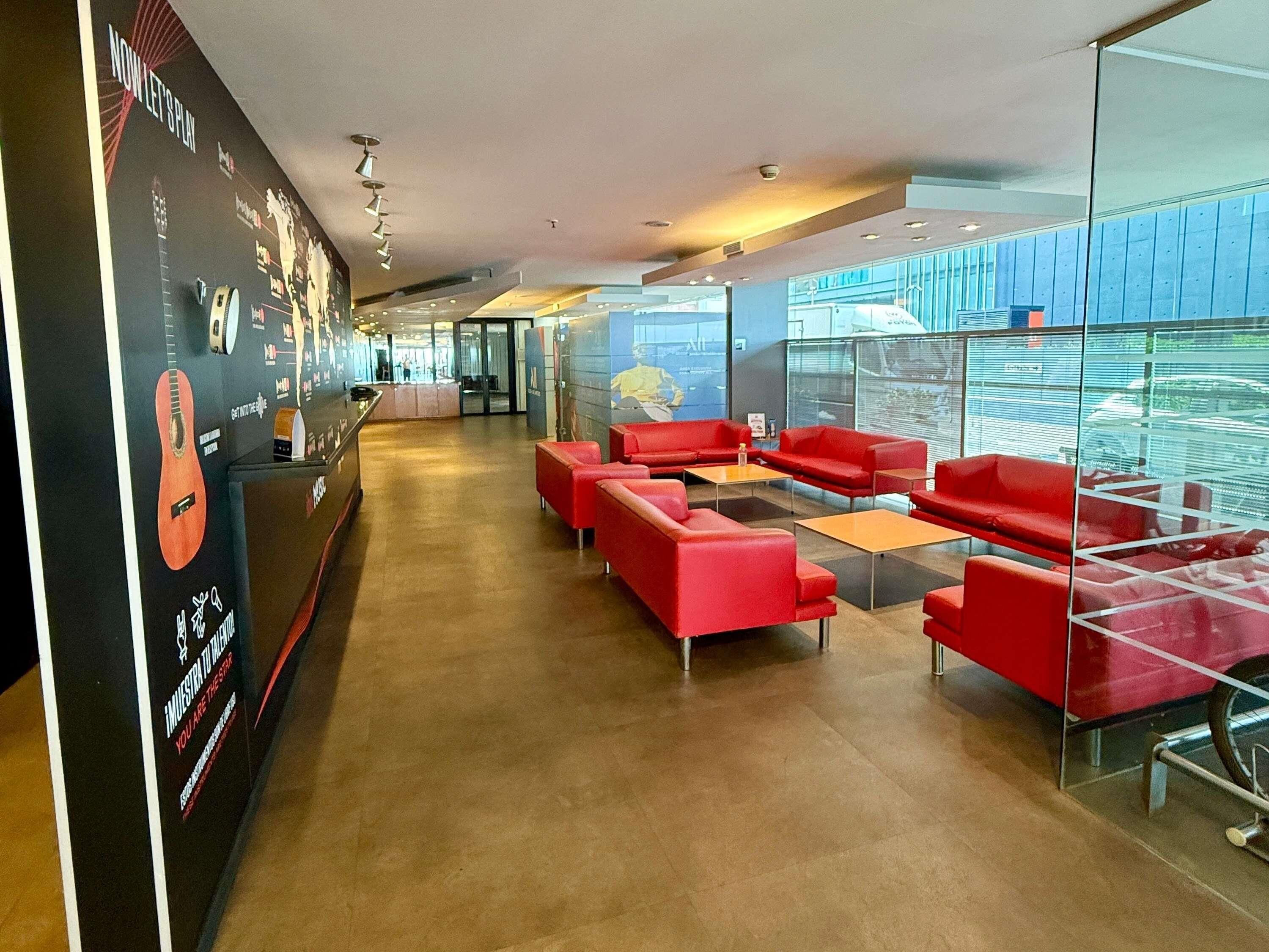 A modern lobby with red seating, a reception desk, and a glass wall offering a view.