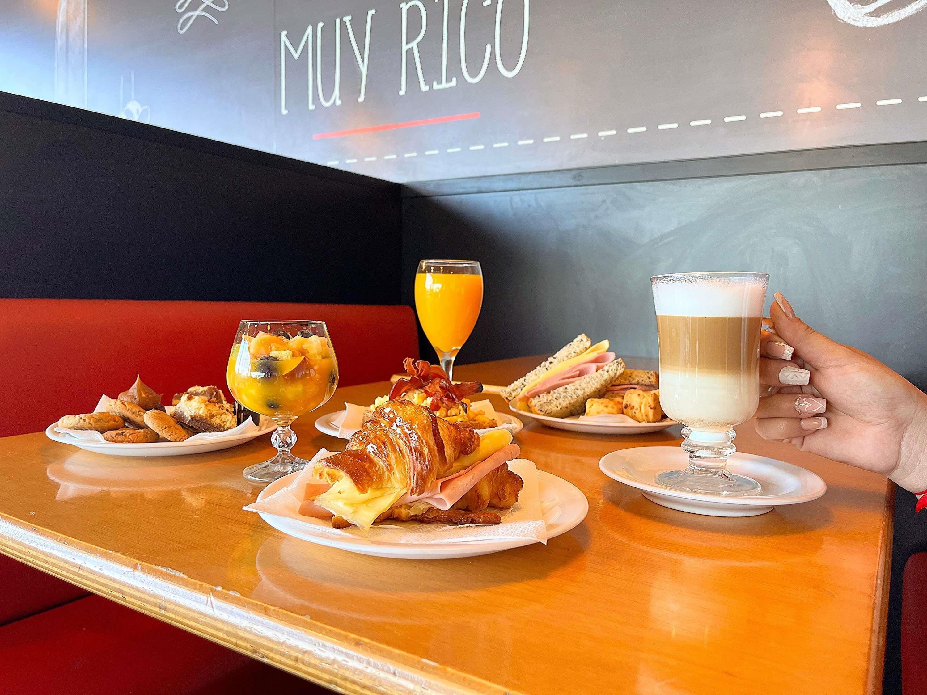 A dining table with plates of food, a glass of orange juice, and a glass of milk.