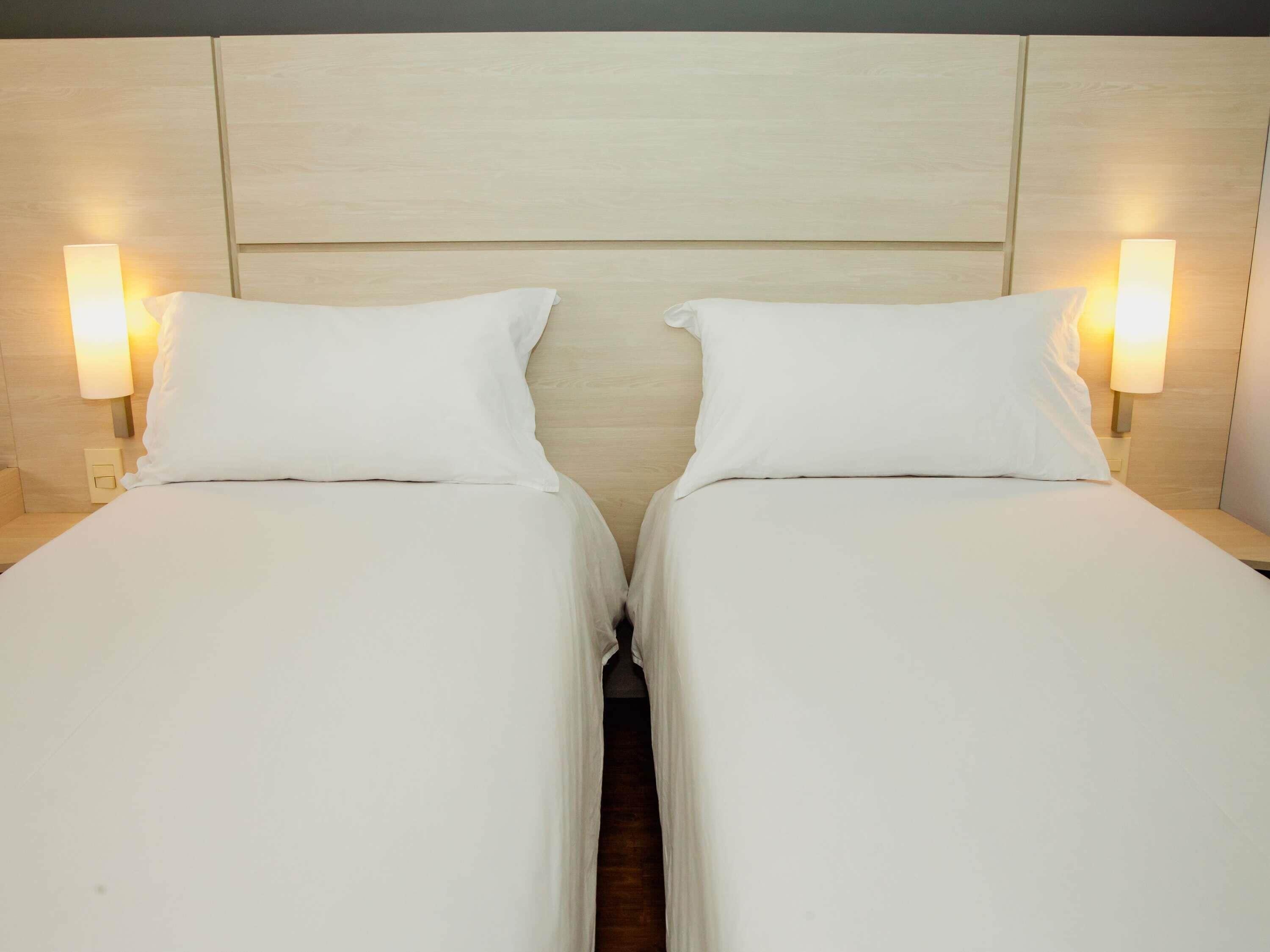 A double bed with a wooden headboard, two bedside lamps, and a neutral color scheme.