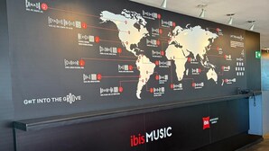 Una pared con un mapa mundial que destaca varios géneros musicales y un letrero que dice "ibis MUSIC".