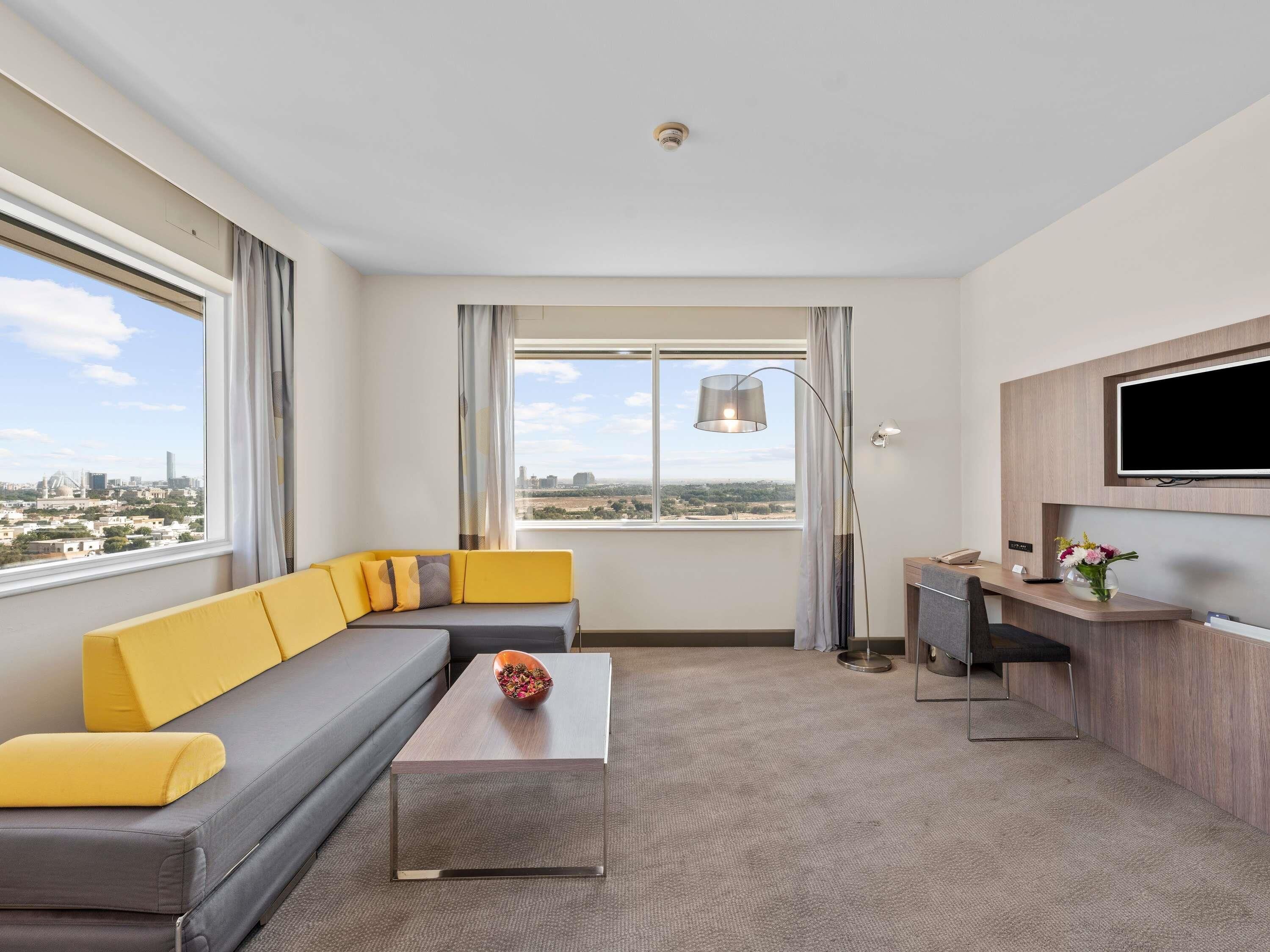 Une chambre d’hôtel moderne équipée d’un canapé, d’une table basse, d’un bureau et d’une télévision.
