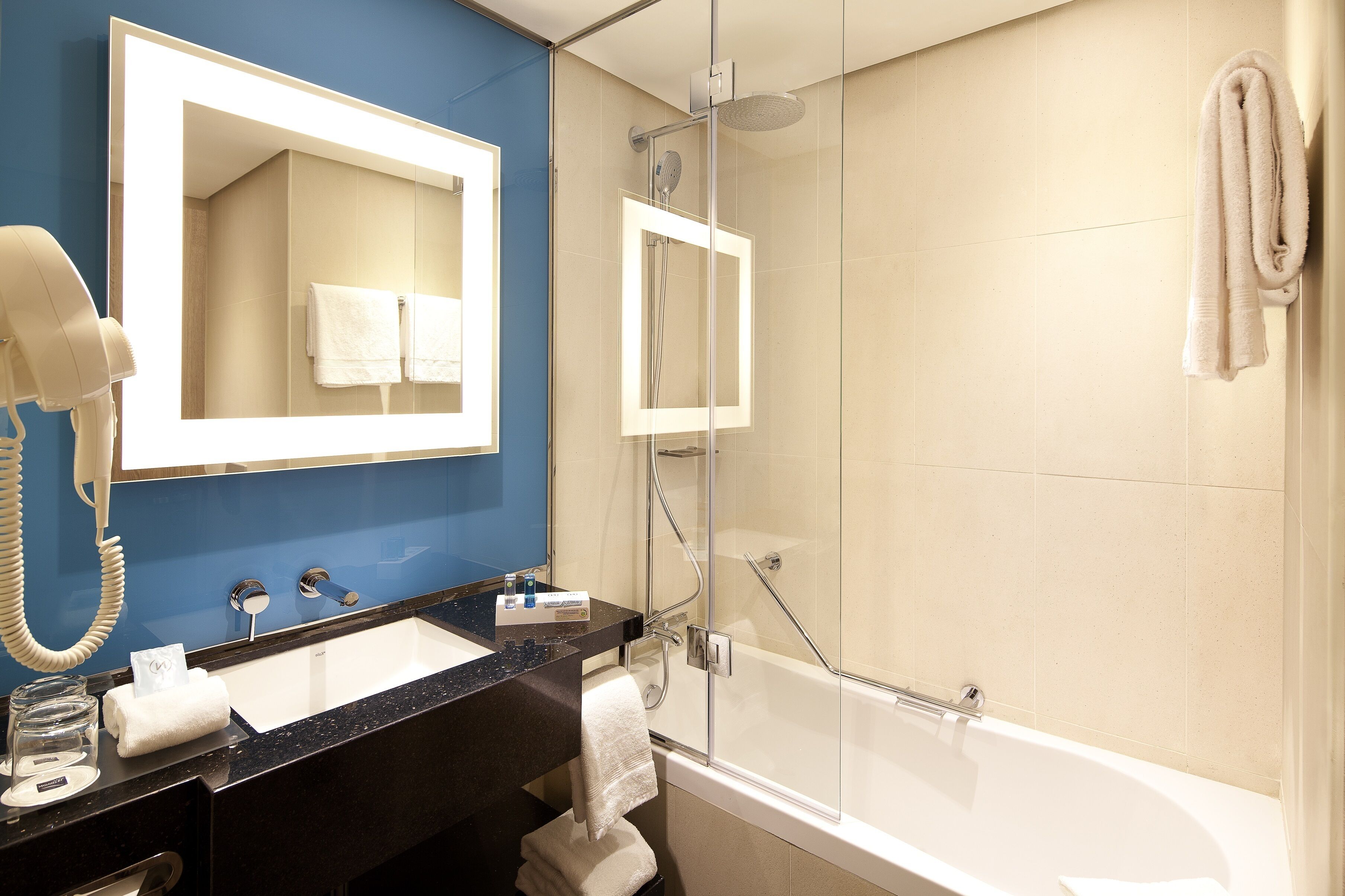 A modern bathroom with a black countertop, white sink, and a glass-enclosed shower.