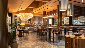 A modern restaurant with a warm interior, wooden flooring, and a bar area. - Novotel World Trade Centre (Dubai)