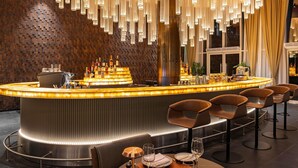 A modern bar area with a curved counter, bar stools, and a unique hanging light fixture. - Novotel World Trade Centre (Dubai)