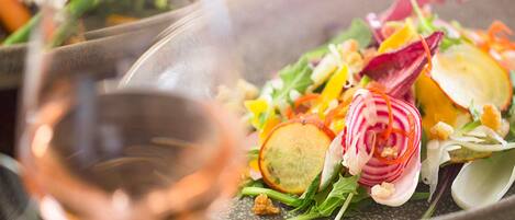 A close-up of a colorful salad with a glass of wine.