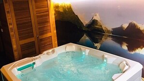 A hot tub with a wooden bench, set against a backdrop of a mountain landscape. - Novotel Queenstown Lakeside (Queenstown)