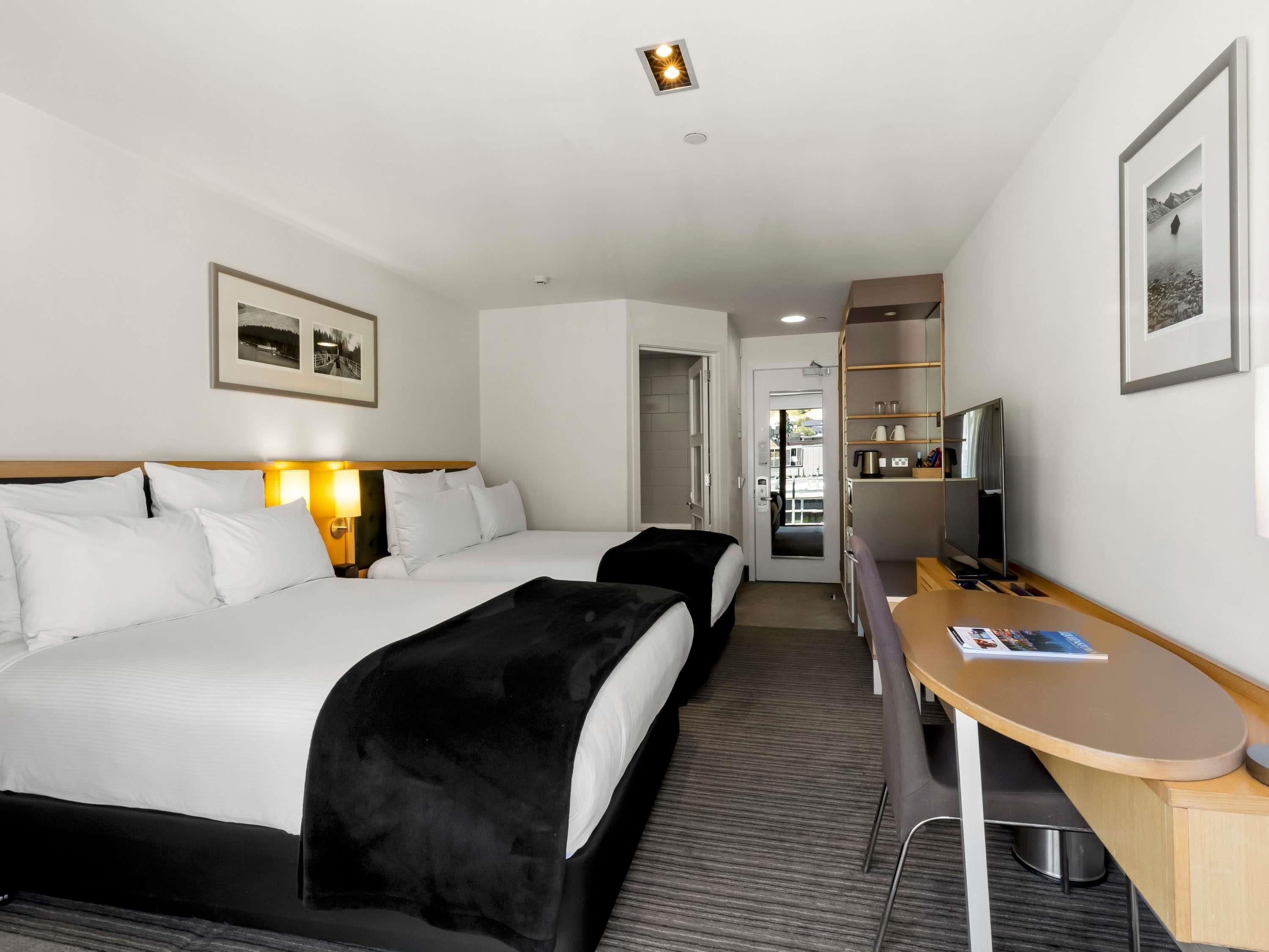 Habitación de hotel con dos camas, un escritorio, un televisor y una kitchenette.