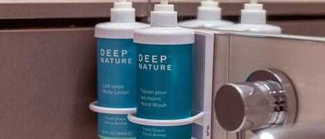 A bathroom with a sink, a mirror, and two bottles of Deep Nature body lotion and hand wash.