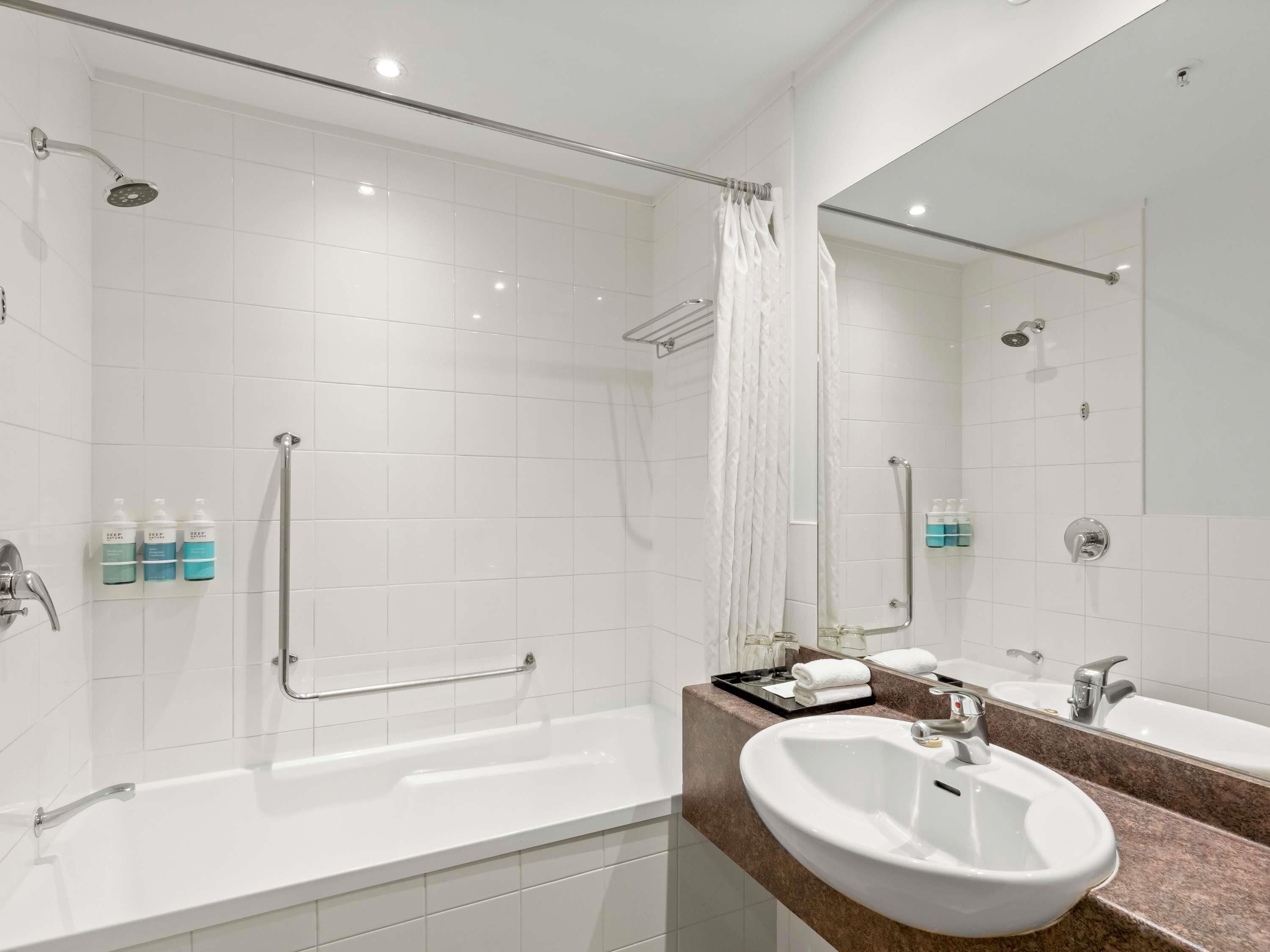 A modern bathroom with a bathtub, a sink, a shower, and a mirror.