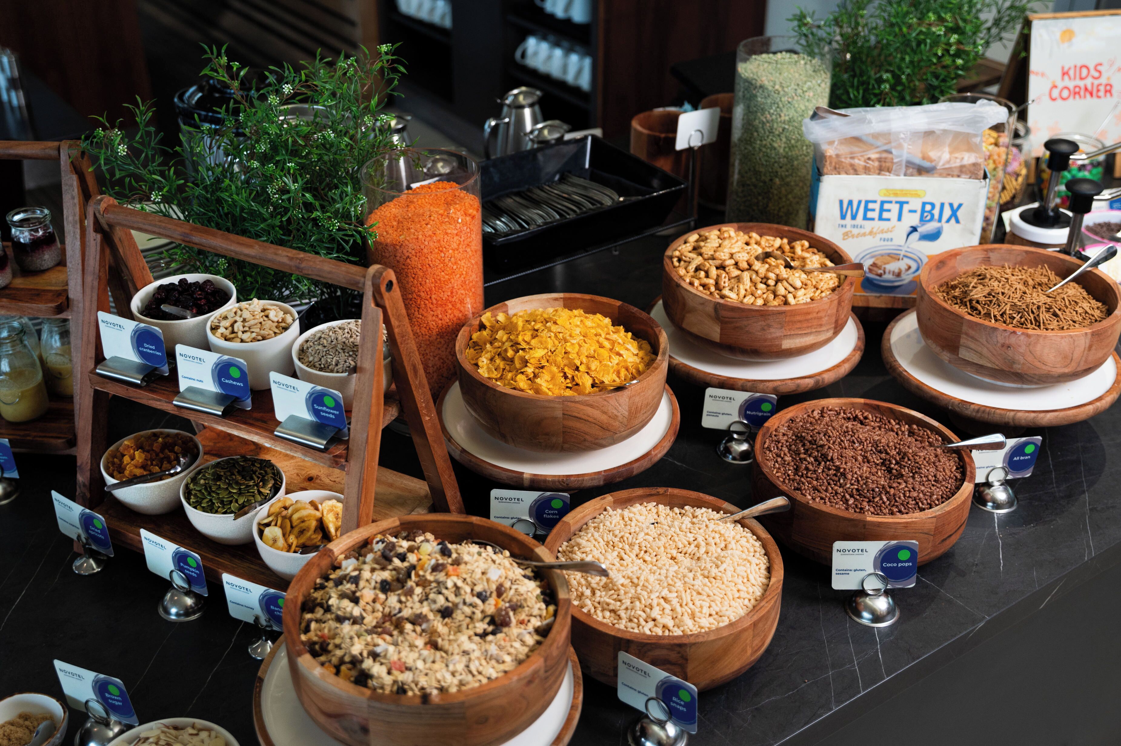 A buffet with various food items in wooden bowls, some labeled with brand names.