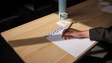 A wooden table with a notepad labeled "NOVOTEL" and a pen.