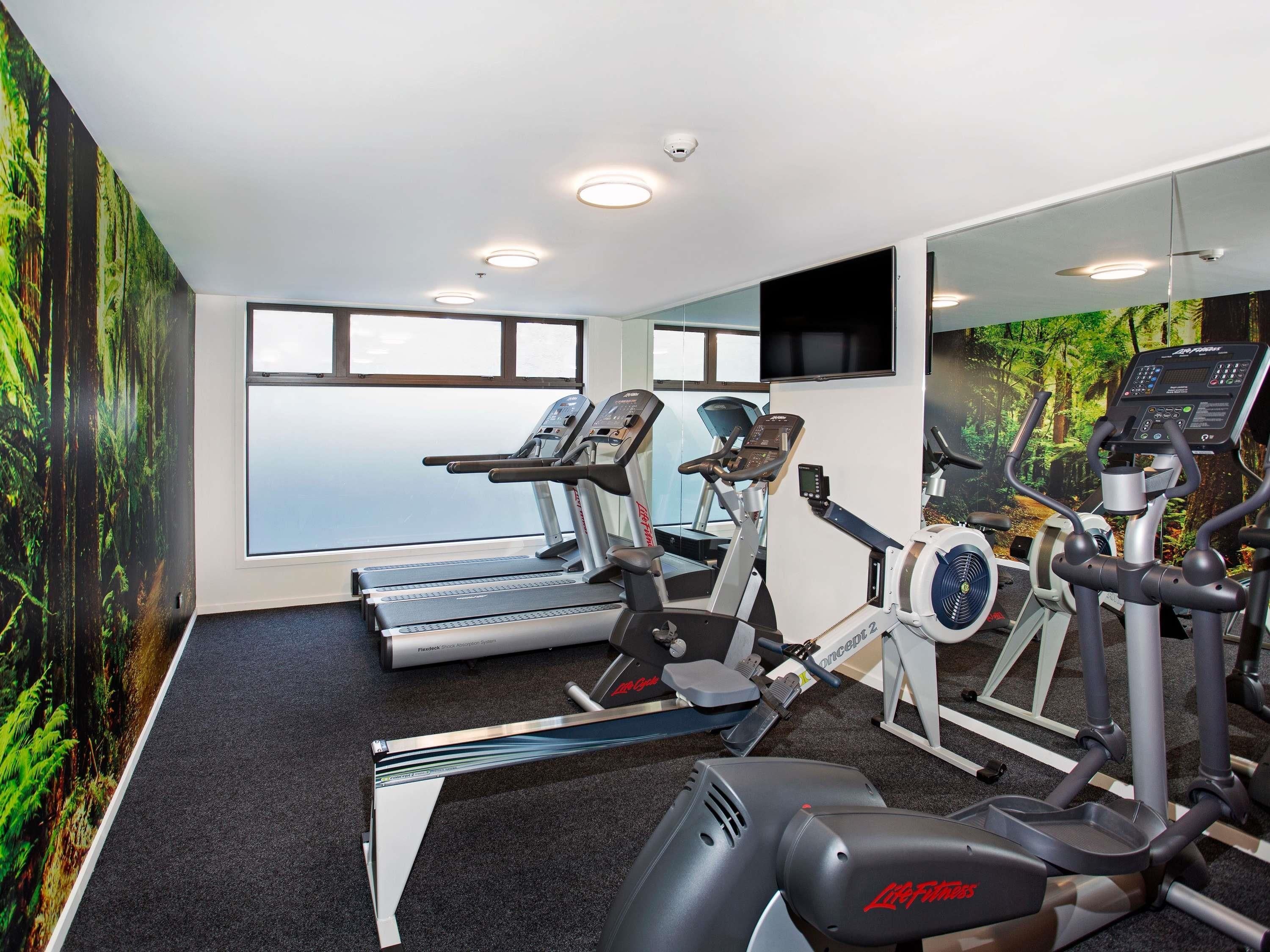 Une salle de sport équipée de tapis de course, d’un vélo elliptique et d’un rameur.