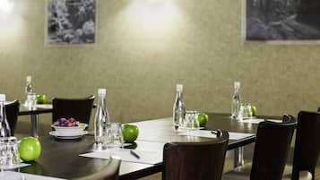 A conference room with a long table, chairs, water bottles, glasses, and apples.